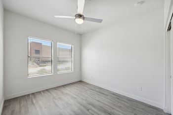 an empty living room with a ceiling fan and two windows